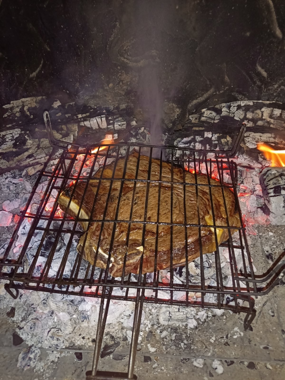 Une côte de bœuf grille sur les braises de la cheminée