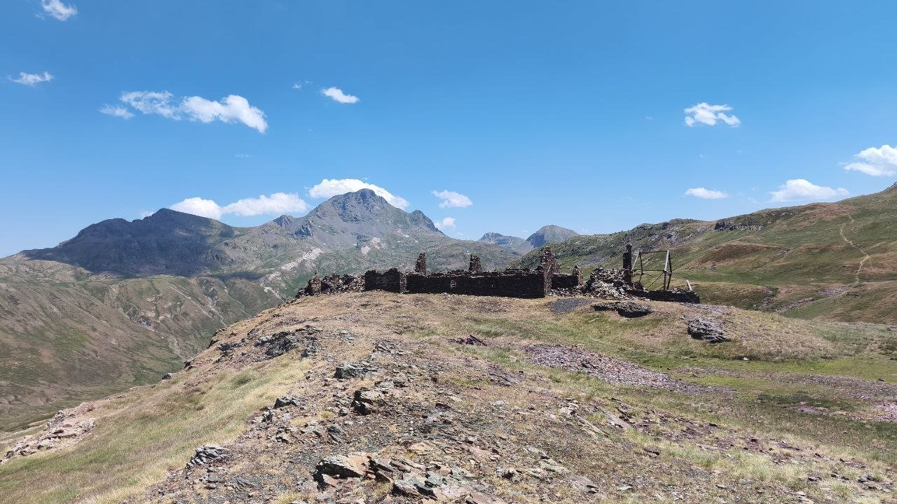 Ruines des bâtiments d'une ancienne mine sur une crête d'estive, face aux sommets