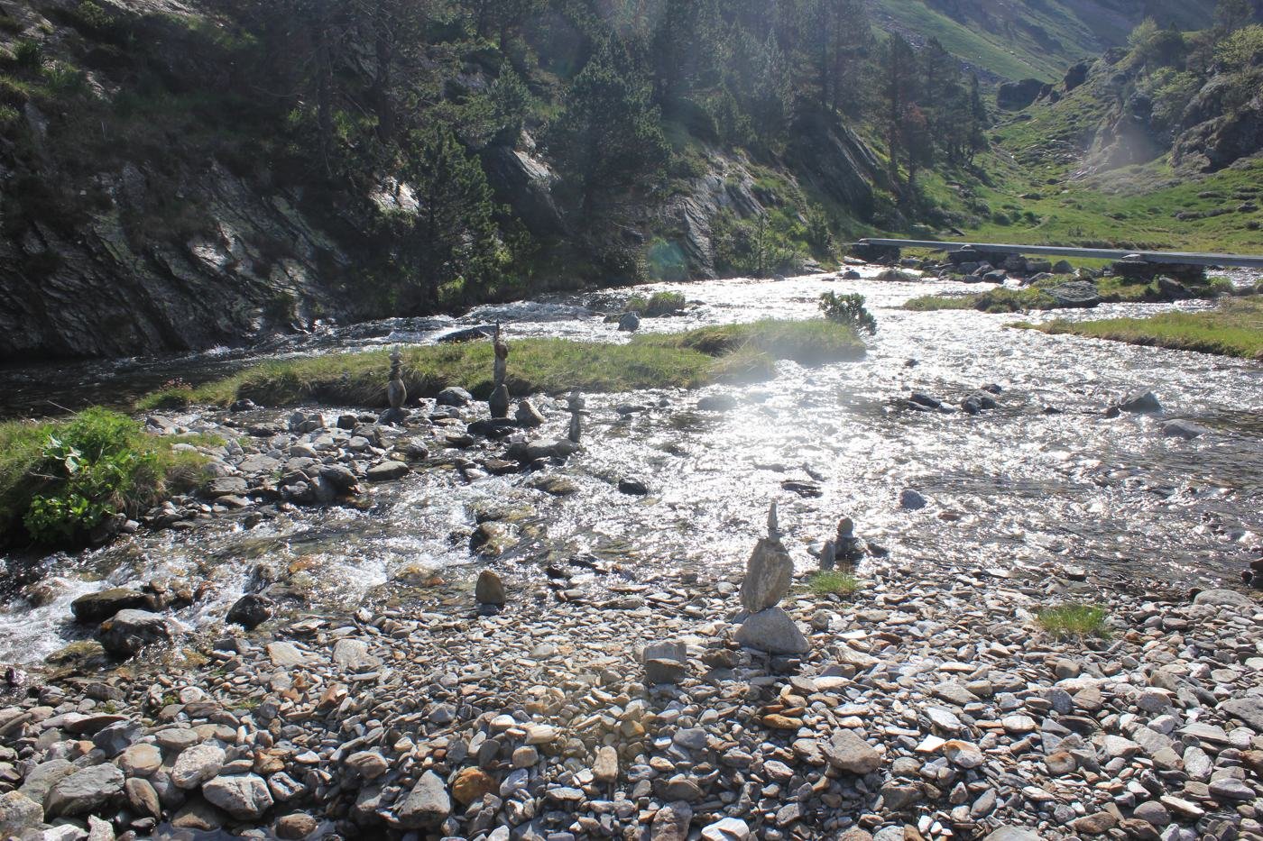Torrent de montagne scintillant au soleil, jalonné de petits cairns