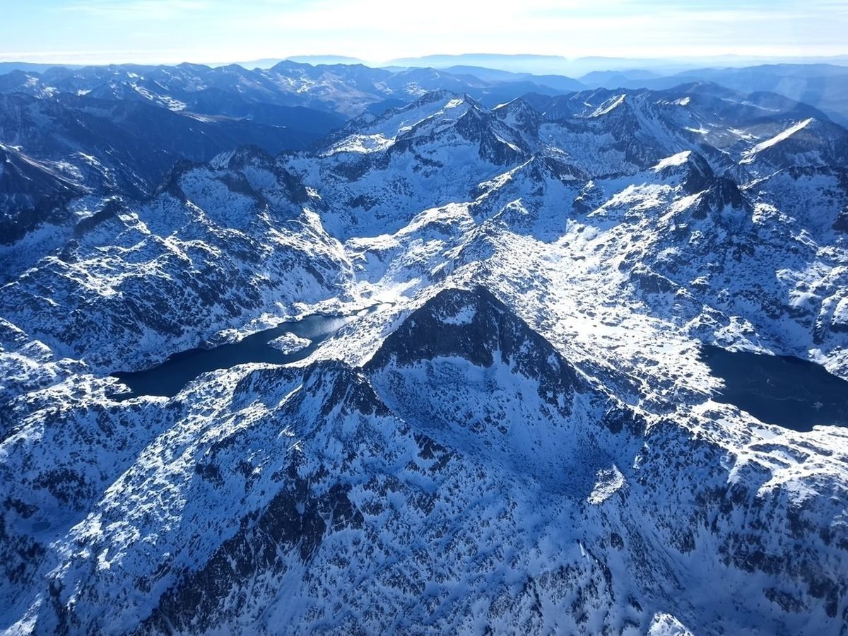 Vue d'avion sur des crêtes enneigées et deux lacs sombres