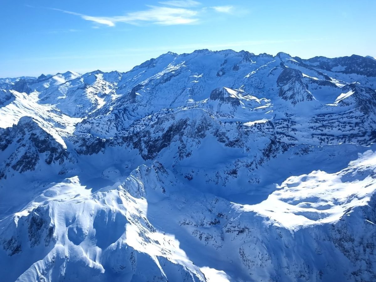Grand massif enneigé sous un ciel bleu, vu d'avion