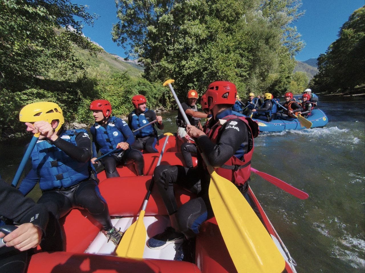 Deux rafts pleins de rires descendent une rivière entre les arbres