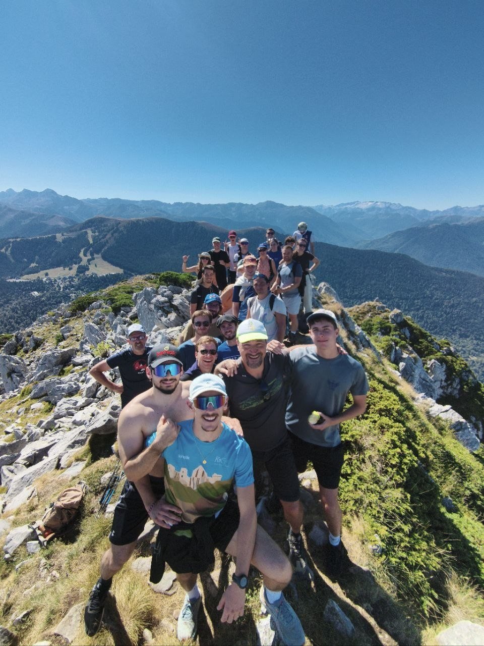 Un grand groupe tout sourire réuni sur une crête rocheuse, face aux Pyrénées