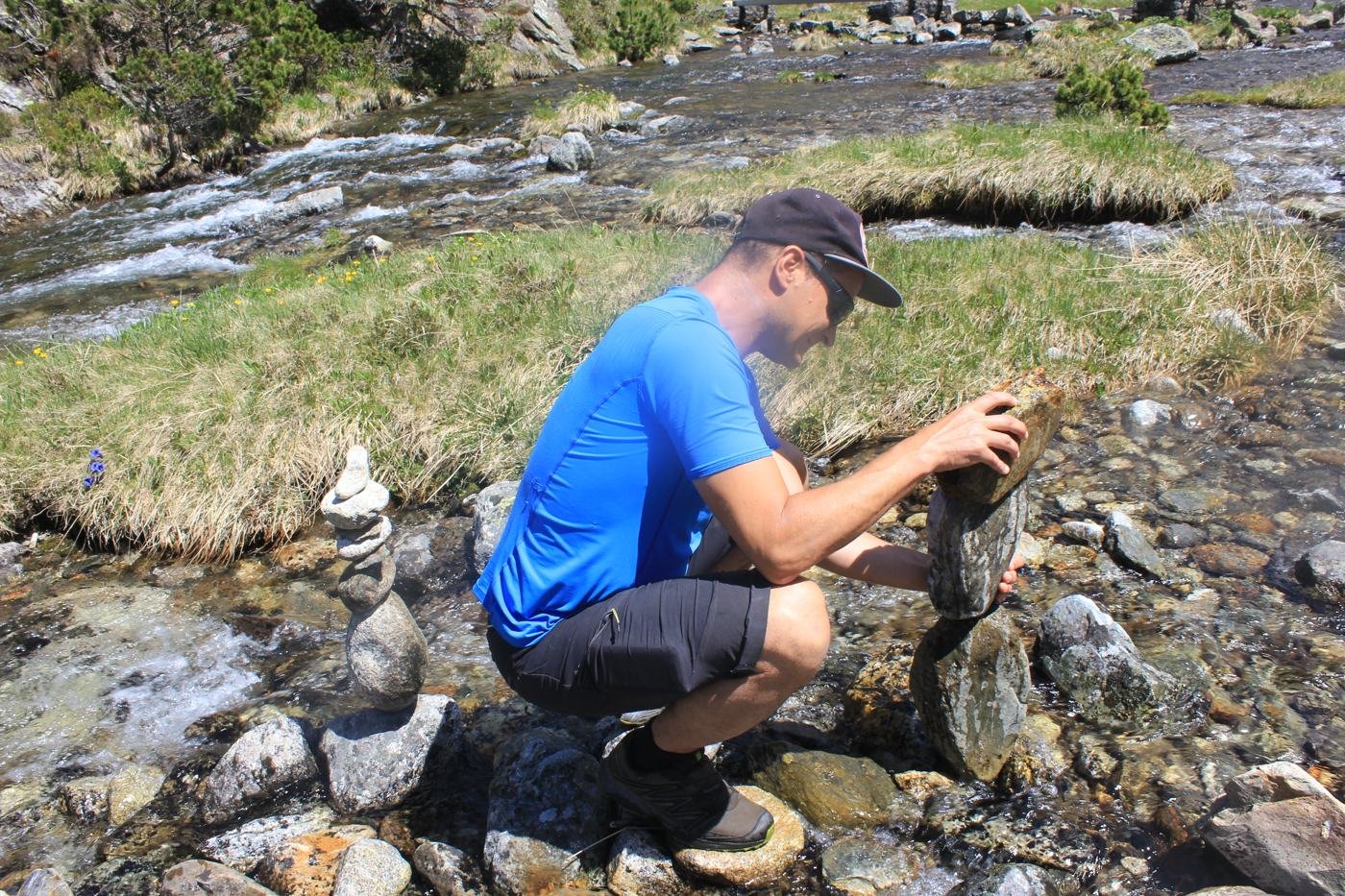 Christophe construit un cairn au bord d'un torrent
