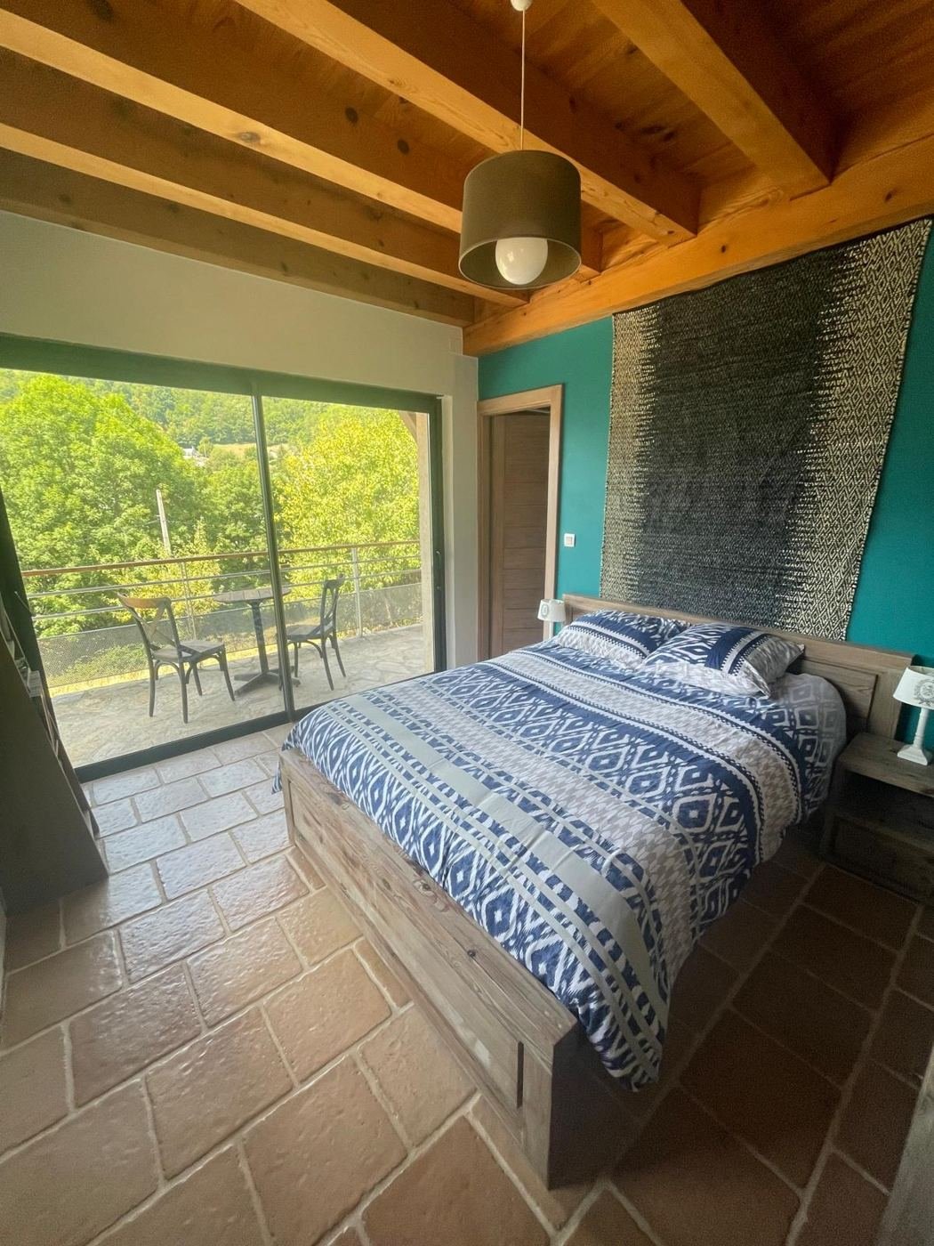 Une chambre du gîte ouverte sur la forêt par une baie vitrée