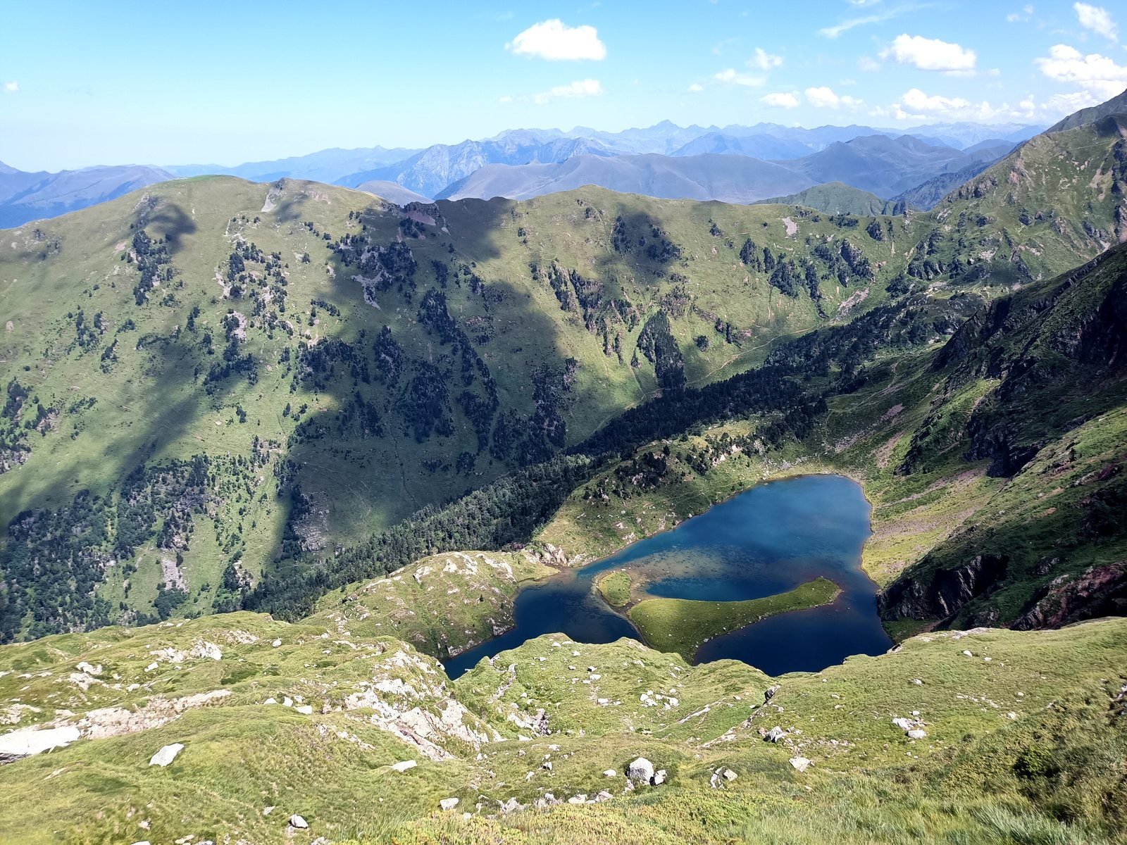 Lac d'altitude et son île d'herbe, au creux d'un cirque verdoyant