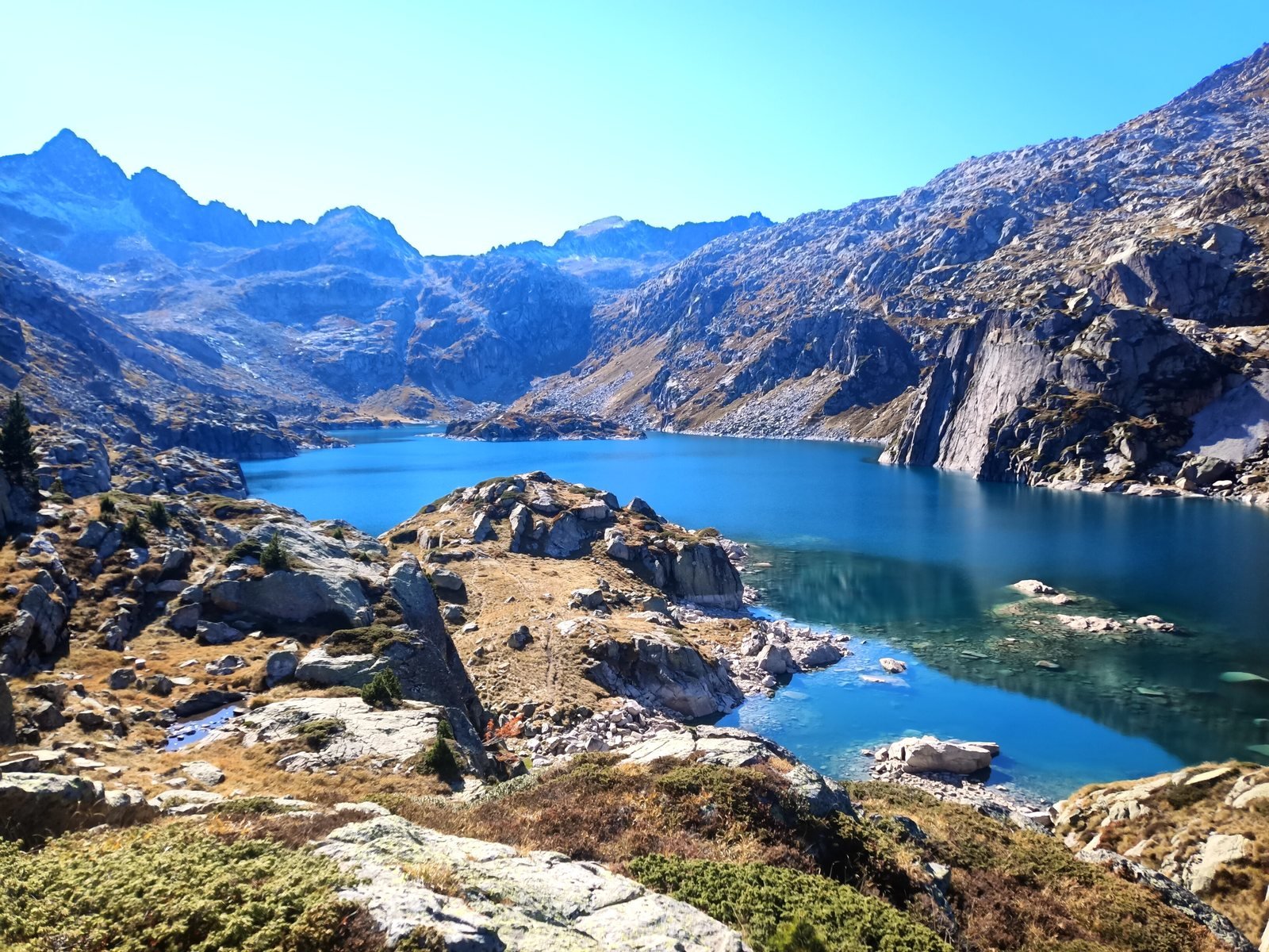 Grand lac d'altitude turquoise entre falaises de granit, à l'automne