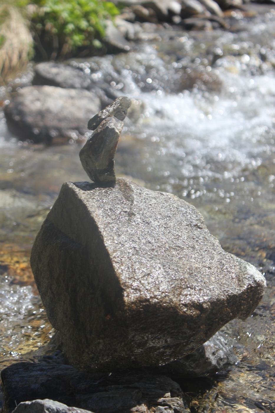 Pierre en équilibre sur un gros rocher au bord de l'eau vive