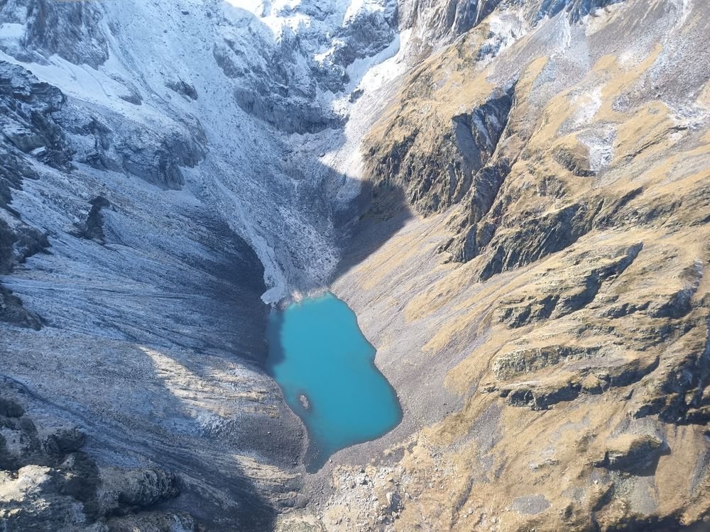 Un lac turquoise au fond d'un cirque, entre neige fraîche et estives dorées